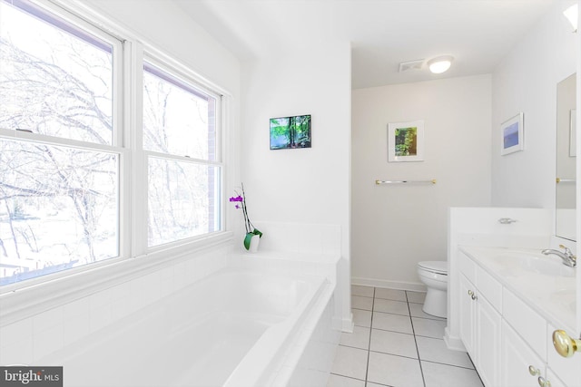 bathroom with toilet, vanity, tile patterned floors, and tiled tub