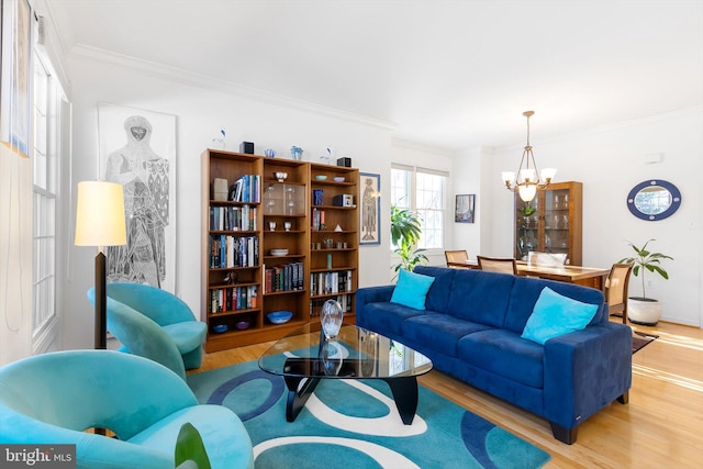 living room featuring an inviting chandelier, light hardwood / wood-style floors, and ornamental molding