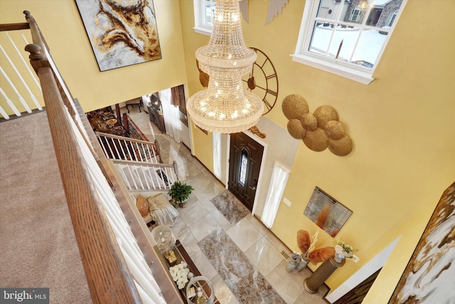 interior space featuring light colored carpet, a high ceiling, and an inviting chandelier