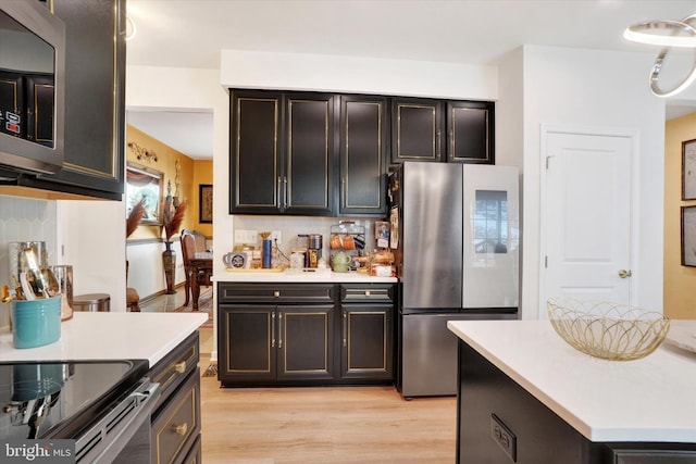 kitchen with light wood-type flooring, stainless steel refrigerator, and tasteful backsplash