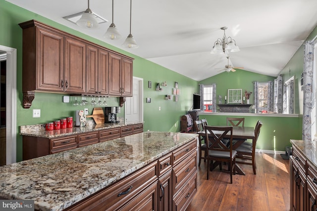 kitchen with pendant lighting, light stone counters, dark hardwood / wood-style floors, lofted ceiling, and ceiling fan with notable chandelier