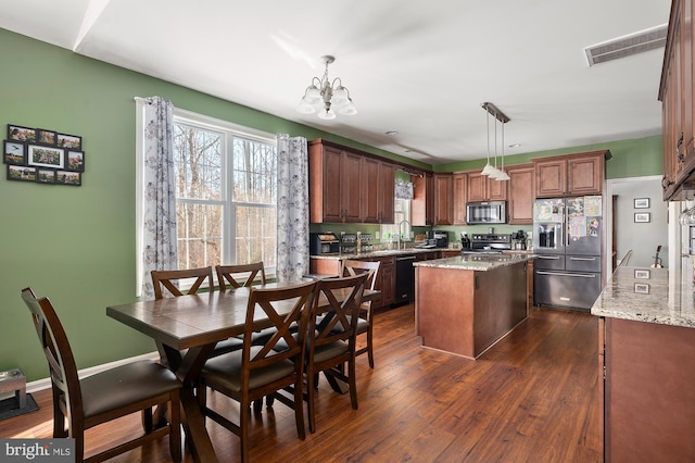 kitchen with stainless steel appliances, decorative light fixtures, a center island, and dark hardwood / wood-style floors