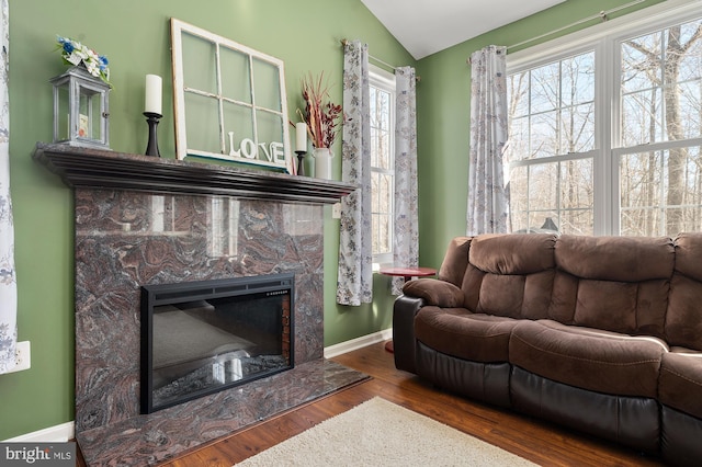 living room featuring a high end fireplace, lofted ceiling, and hardwood / wood-style flooring