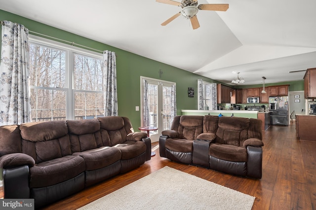 living room featuring dark wood-type flooring, vaulted ceiling, and ceiling fan with notable chandelier