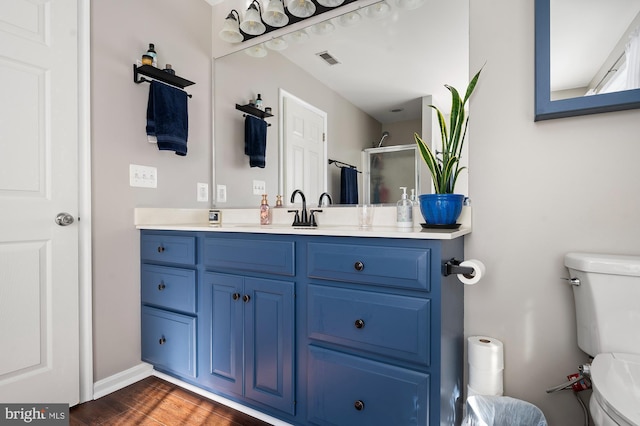 bathroom with wood-type flooring, a shower, vanity, and toilet