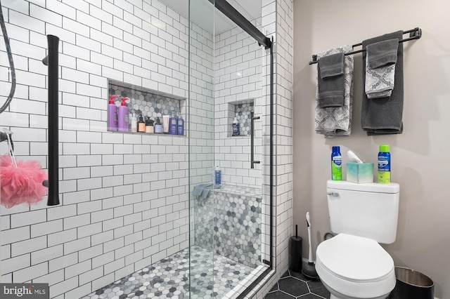 bathroom featuring toilet, tile patterned flooring, and a shower with door