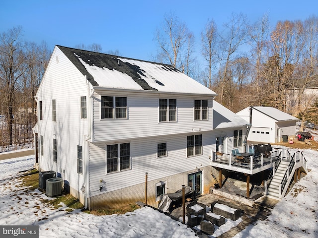 snow covered rear of property with central AC and a wooden deck