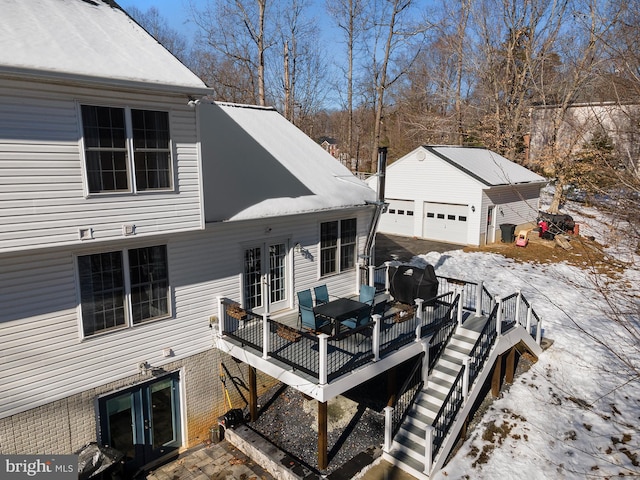 snow covered deck with a garage and an outdoor structure