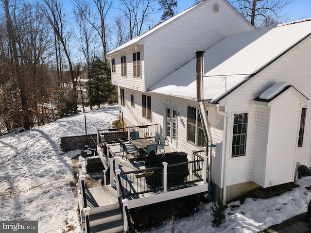 snow covered back of property featuring a deck