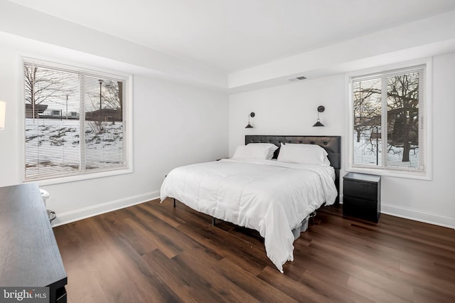 bedroom with dark hardwood / wood-style flooring and multiple windows