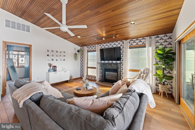 living room featuring light hardwood / wood-style flooring, vaulted ceiling, ceiling fan, wood ceiling, and a fireplace