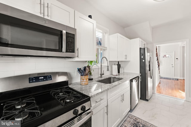 kitchen featuring light stone counters, white cabinets, appliances with stainless steel finishes, and sink