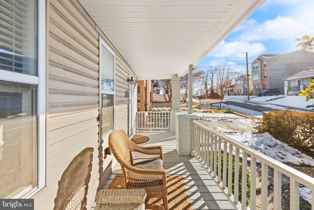 snow covered back of property with a porch