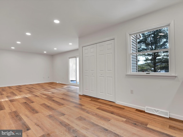 unfurnished bedroom with light hardwood / wood-style floors, a closet, and multiple windows