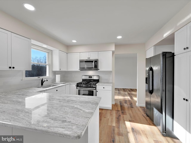 kitchen featuring stainless steel appliances, white cabinetry, and kitchen peninsula