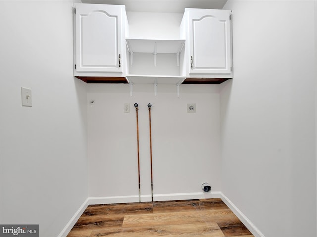 clothes washing area featuring electric dryer hookup, cabinets, wood-type flooring, and washer hookup