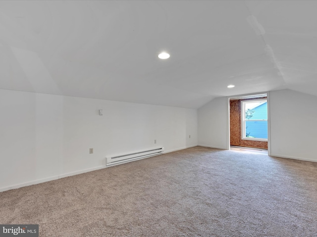 additional living space featuring light colored carpet, vaulted ceiling, and a baseboard heating unit