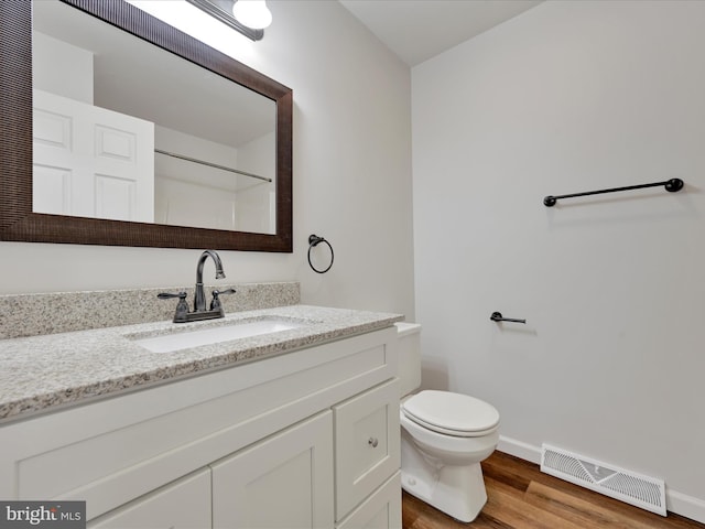 bathroom with toilet, vanity, and hardwood / wood-style flooring