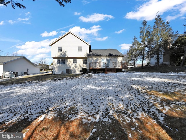 snow covered rear of property with a wooden deck