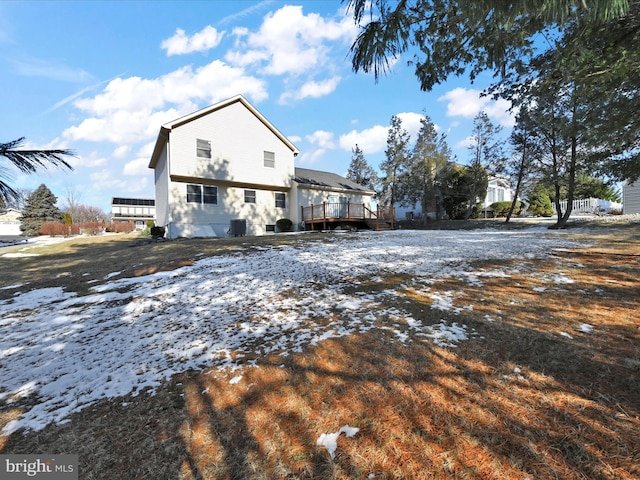 snow covered back of property featuring a wooden deck