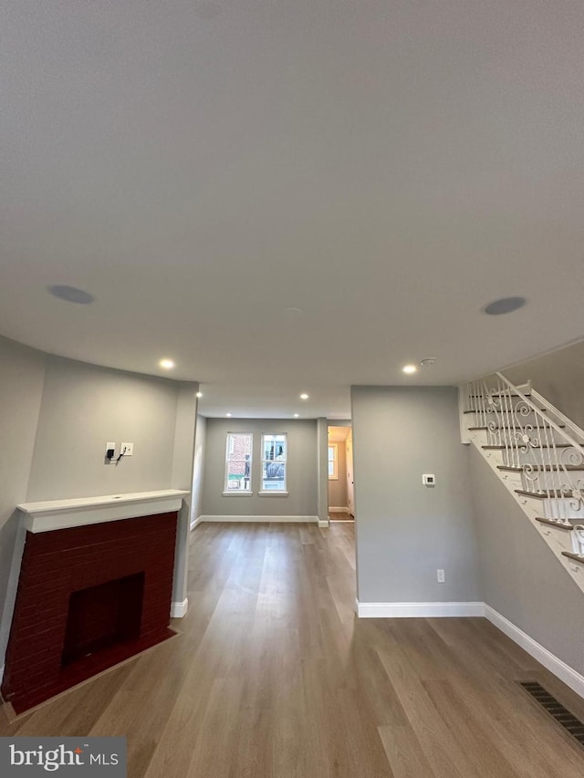 unfurnished living room with a fireplace and light wood-type flooring