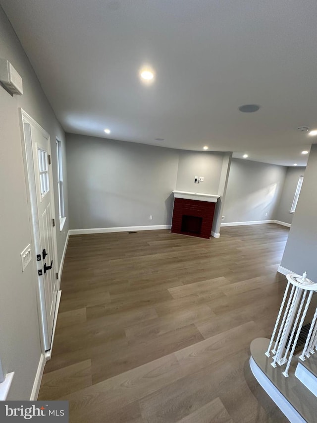 basement with hardwood / wood-style floors, a healthy amount of sunlight, and a brick fireplace