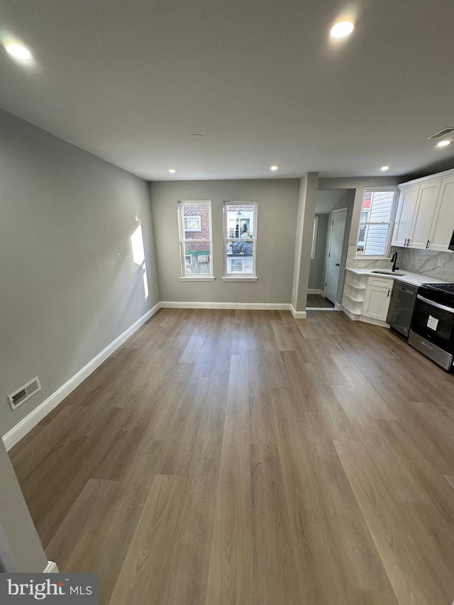 unfurnished living room featuring light hardwood / wood-style floors, plenty of natural light, and sink