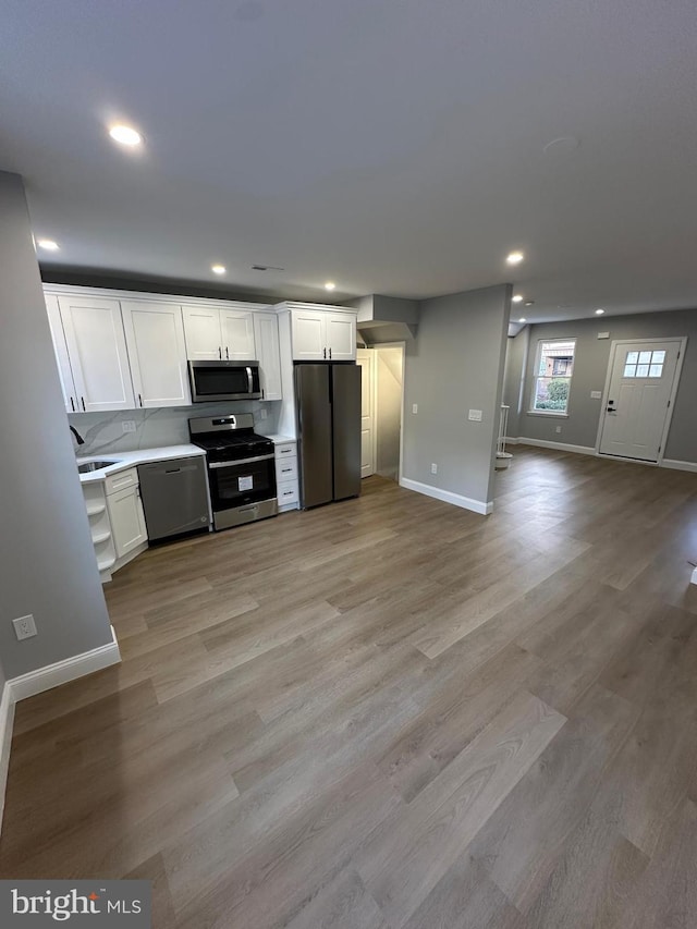 kitchen with white cabinets, sink, appliances with stainless steel finishes, and light hardwood / wood-style flooring