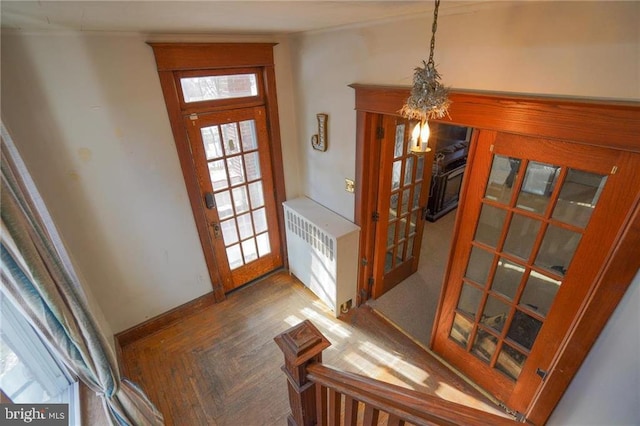 entryway with dark parquet flooring, radiator, and a chandelier