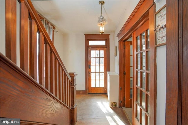 entryway with light wood-type flooring and an inviting chandelier