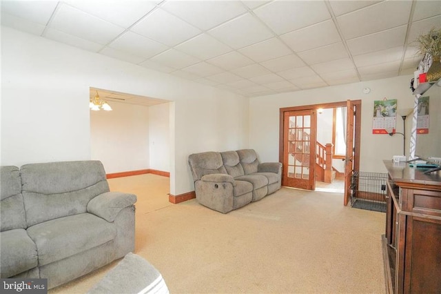 living room featuring a paneled ceiling, ceiling fan, and light colored carpet