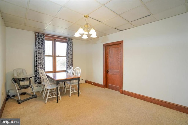 carpeted dining area featuring a paneled ceiling and a notable chandelier