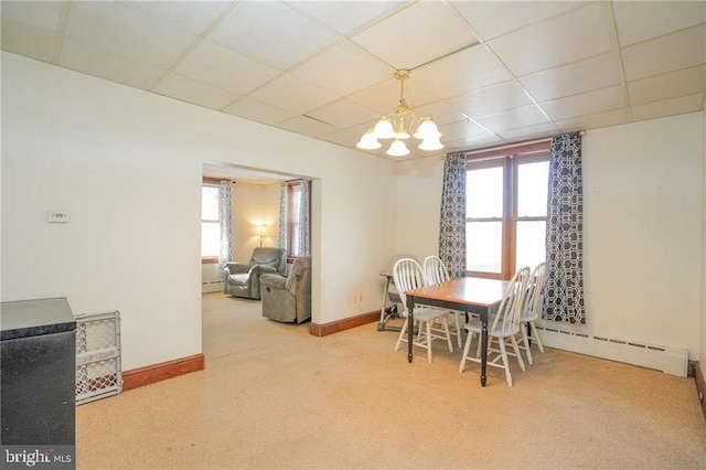 carpeted dining room with a drop ceiling, baseboard heating, and a chandelier