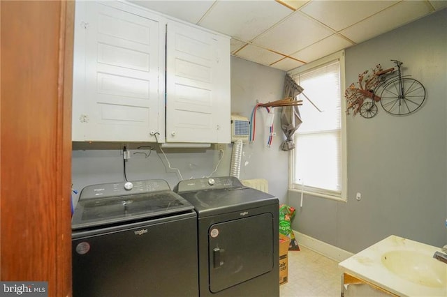 clothes washing area featuring washer and clothes dryer, cabinets, and sink