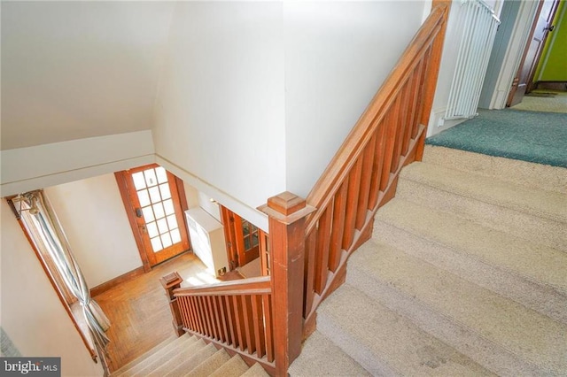 staircase featuring carpet flooring and vaulted ceiling