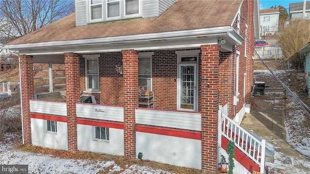 snow covered property with covered porch