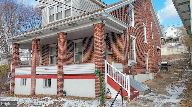 snow covered property with covered porch