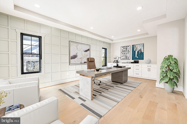 home office with plenty of natural light, a tray ceiling, and light wood-type flooring