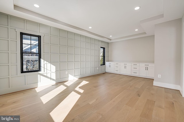 spare room featuring light wood-type flooring and a tray ceiling