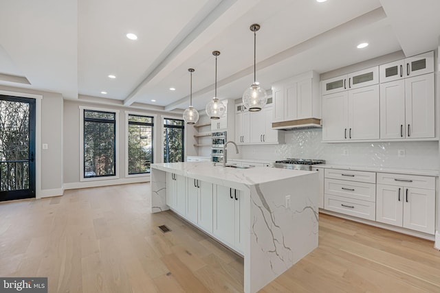 kitchen featuring white cabinetry, sink, a kitchen island with sink, and light stone counters