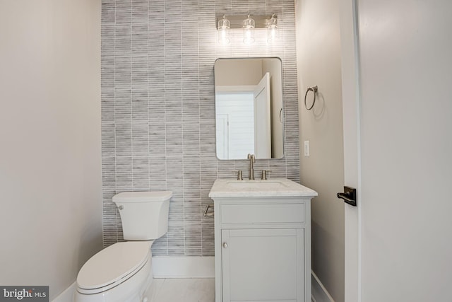 bathroom with tile patterned flooring, vanity, tile walls, and toilet