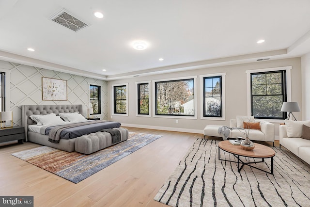 bedroom with a raised ceiling and light wood-type flooring