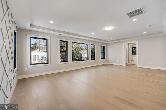 unfurnished room featuring a raised ceiling and light hardwood / wood-style flooring