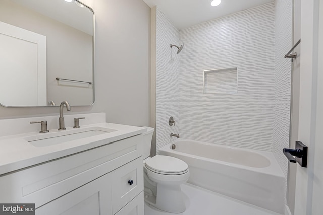 full bathroom with tiled shower / bath, vanity, and toilet