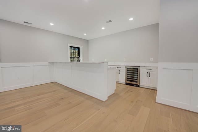 bar featuring white cabinetry, light hardwood / wood-style flooring, and beverage cooler