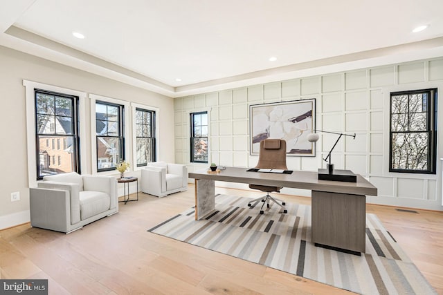 home office featuring light hardwood / wood-style floors and a raised ceiling