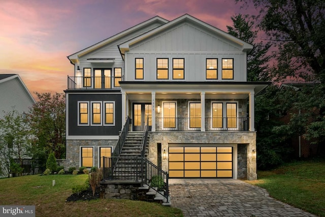 view of front of house featuring a garage, a balcony, and a lawn