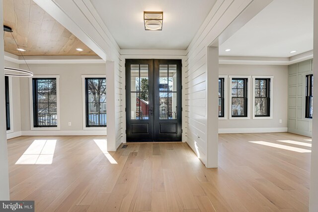 entrance foyer featuring french doors, a healthy amount of sunlight, and light hardwood / wood-style floors