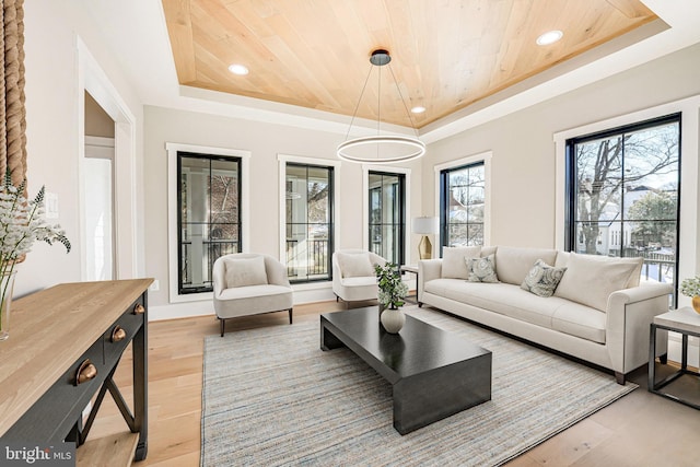 living room with light hardwood / wood-style flooring, wooden ceiling, and a raised ceiling