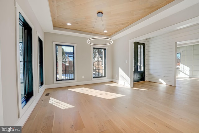 unfurnished dining area featuring wood ceiling, a tray ceiling, and light hardwood / wood-style floors